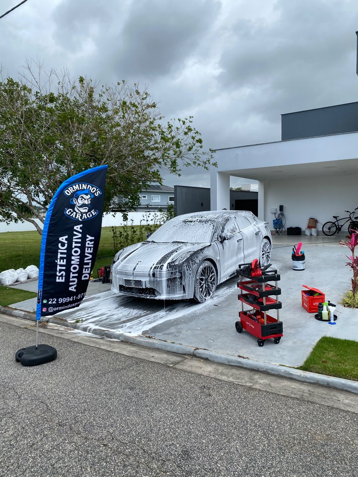 Carro esportivo coberto de espuma durante atendimento delivery com equipamentos profissionais